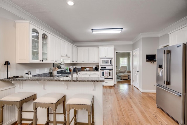 kitchen featuring oven, a breakfast bar area, built in microwave, high end refrigerator, and a peninsula