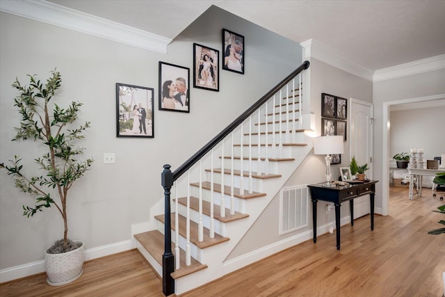 stairs with visible vents, ornamental molding, baseboards, and wood finished floors