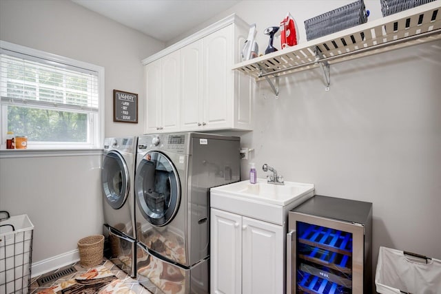 laundry area featuring cabinet space, a sink, beverage cooler, separate washer and dryer, and baseboards