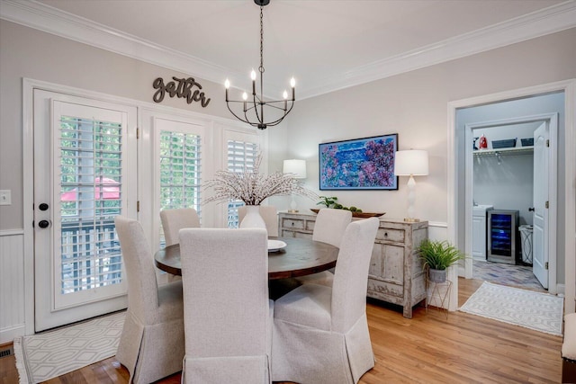 dining room featuring light wood-type flooring, ornamental molding, wine cooler, and a chandelier