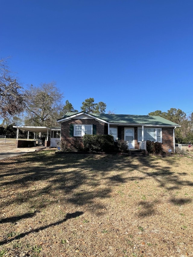 ranch-style home featuring a front lawn and a carport