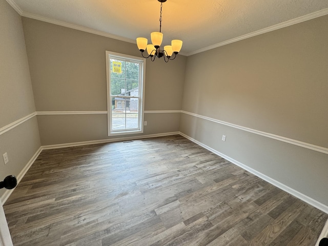 unfurnished room with dark hardwood / wood-style flooring, ornamental molding, a textured ceiling, and an inviting chandelier