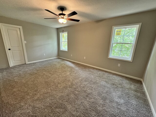 carpeted empty room with ceiling fan and a textured ceiling