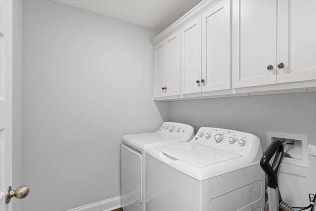 clothes washing area with separate washer and dryer and cabinets