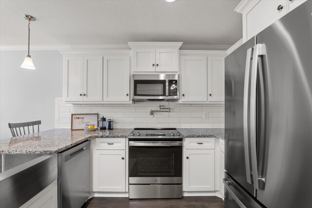 kitchen with light stone countertops, white cabinets, decorative light fixtures, and appliances with stainless steel finishes