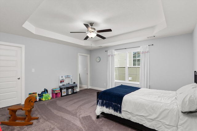 carpeted bedroom with a tray ceiling and ceiling fan