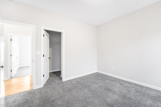 unfurnished bedroom with a walk in closet, dark carpet, and a closet