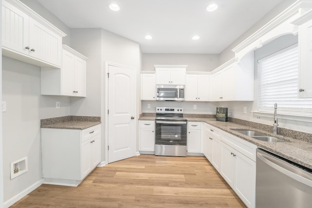 kitchen featuring white cabinets, stone countertops, stainless steel appliances, and sink