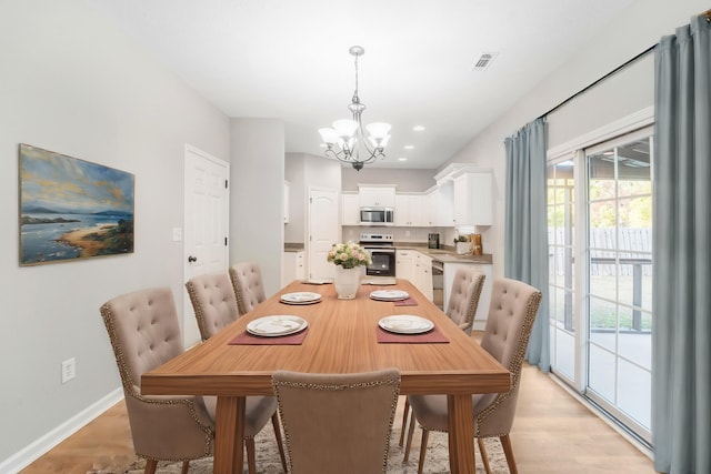 dining room with light wood-type flooring and an inviting chandelier