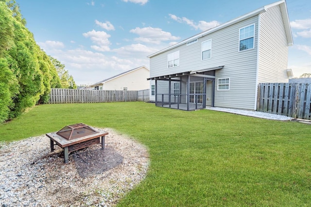 rear view of house featuring a lawn, a sunroom, and a fire pit