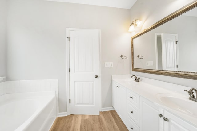 bathroom featuring hardwood / wood-style flooring, vanity, and a bath