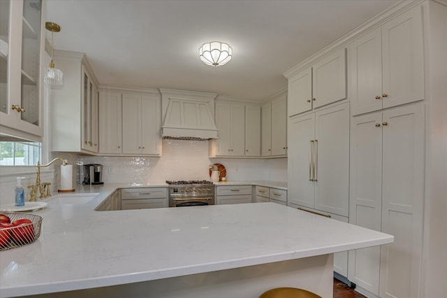 508 Scotts Way, Augusta, GA 30909 - kitchen featuring premium range hood, backsplash, glass insert cabinets, a peninsula, and decorative light fixtures