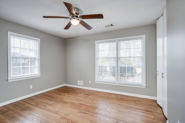 unfurnished room featuring visible vents, plenty of natural light, and baseboards