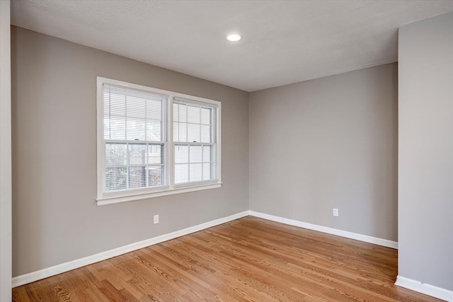 spare room featuring baseboards and light wood-style flooring