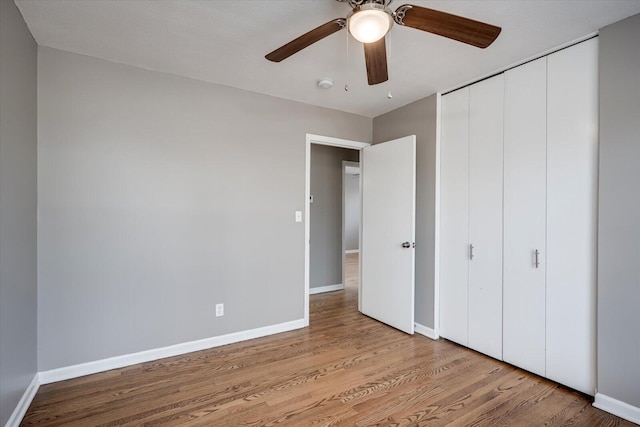 unfurnished bedroom featuring a closet, ceiling fan, baseboards, and wood finished floors