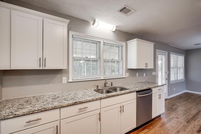 kitchen with stainless steel dishwasher, wood finished floors, plenty of natural light, white cabinetry, and a sink