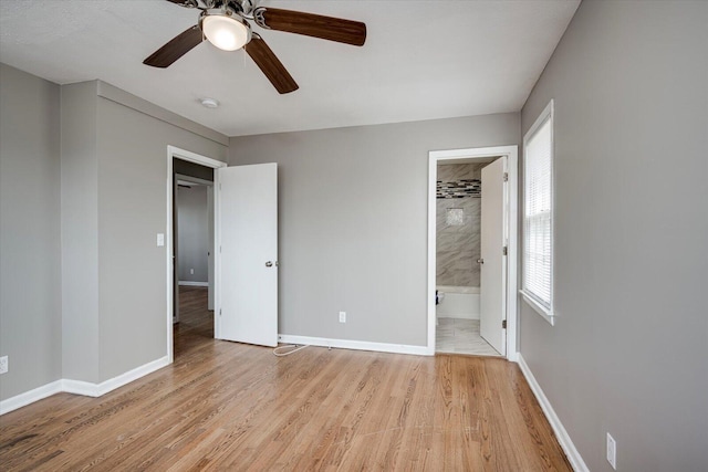 unfurnished bedroom with ensuite bath, wood finished floors, baseboards, and ceiling fan