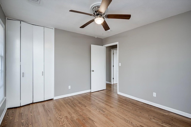 unfurnished bedroom featuring a closet, ceiling fan, light wood-type flooring, and baseboards