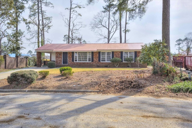 ranch-style home with metal roof, brick siding, and concrete driveway