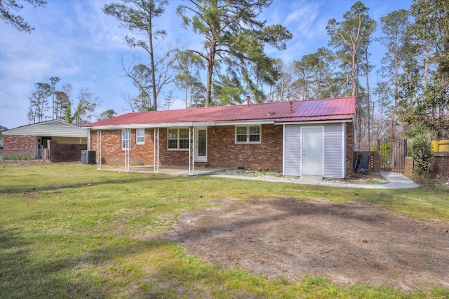 rear view of house featuring brick siding, fence, a lawn, cooling unit, and metal roof