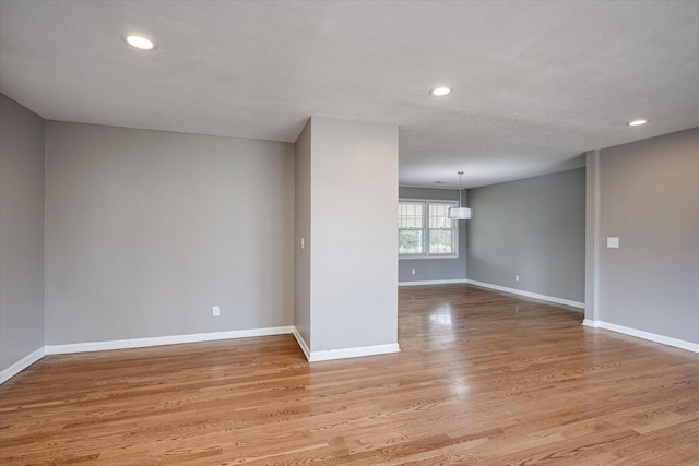 spare room featuring recessed lighting, baseboards, and light wood finished floors