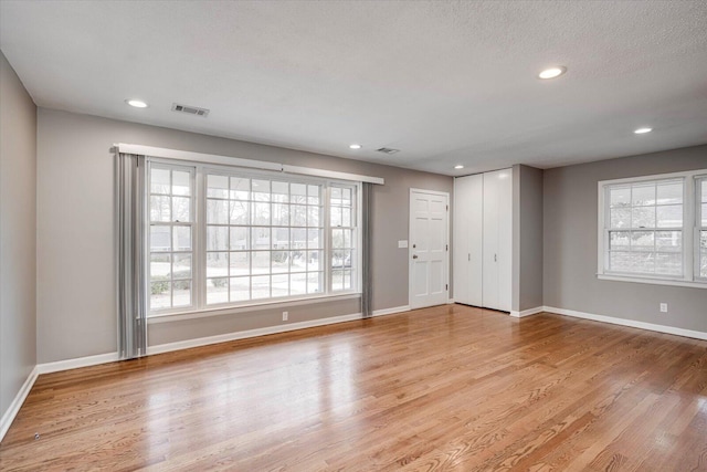 unfurnished room with visible vents, a healthy amount of sunlight, and light wood-style floors