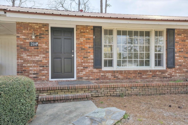 property entrance with metal roof, brick siding, and covered porch