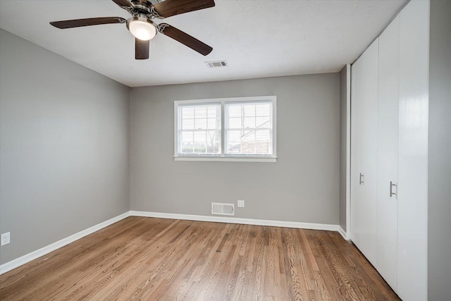 unfurnished bedroom with a closet, visible vents, baseboards, and wood finished floors