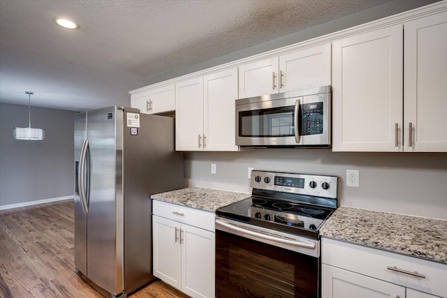 kitchen with light stone counters, white cabinetry, stainless steel appliances, and light wood-type flooring