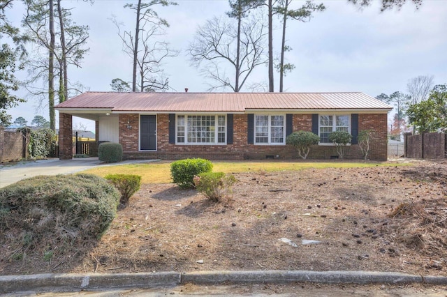 ranch-style house featuring brick siding, driveway, metal roof, and fence