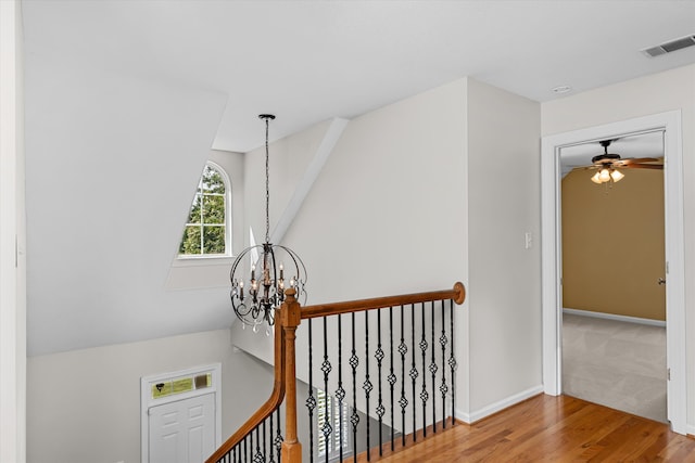 corridor with hardwood / wood-style floors and an inviting chandelier