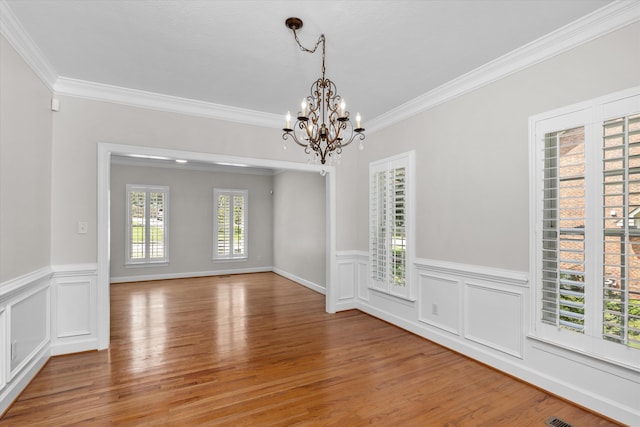 empty room featuring hardwood / wood-style floors, a notable chandelier, and ornamental molding