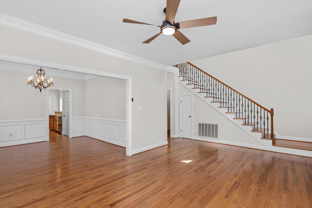 unfurnished living room with wood-type flooring, ceiling fan with notable chandelier, and ornamental molding