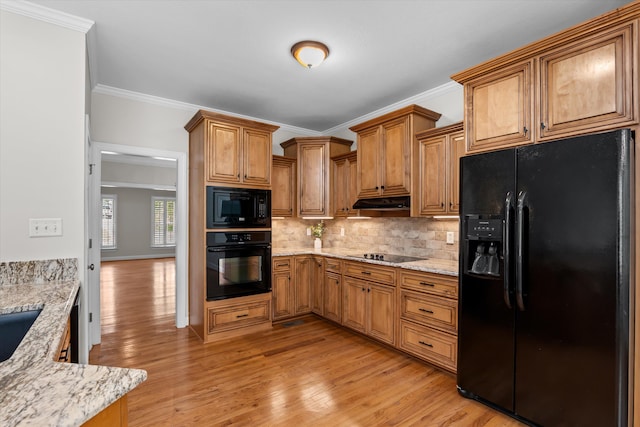 kitchen featuring tasteful backsplash, light stone counters, light hardwood / wood-style flooring, crown molding, and black appliances