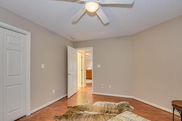 bedroom with ceiling fan, a closet, a textured ceiling, and light hardwood / wood-style flooring