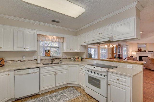 kitchen featuring white appliances, sink, a textured ceiling, white cabinetry, and kitchen peninsula