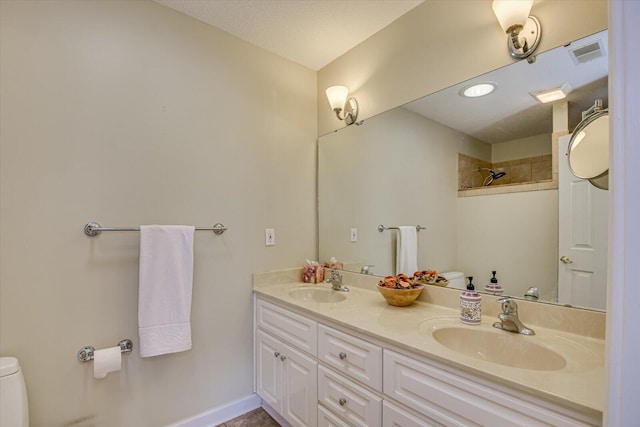 bathroom with a shower, vanity, a textured ceiling, and toilet