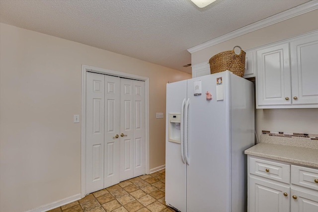 kitchen with white cabinetry, white fridge with ice dispenser, and a textured ceiling