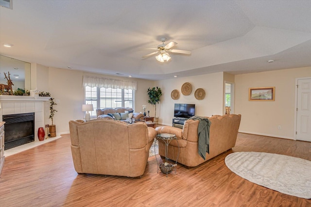 living room with ceiling fan, light hardwood / wood-style flooring, and a tray ceiling