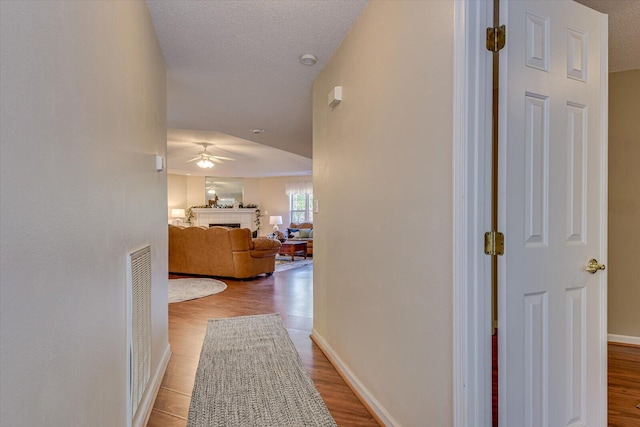 corridor featuring light hardwood / wood-style floors and a textured ceiling