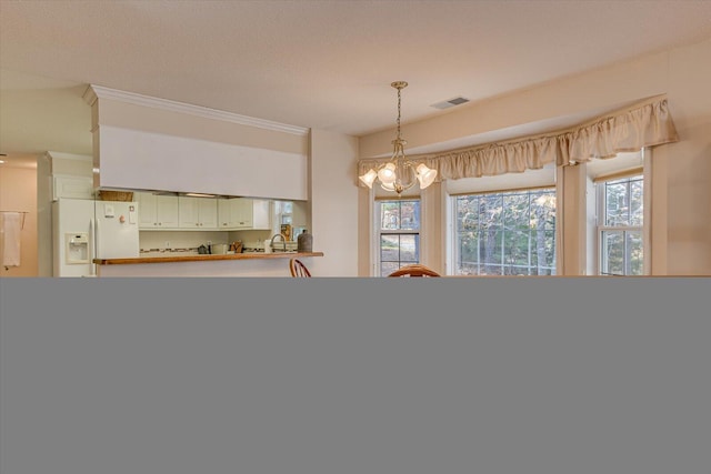 dining area featuring a notable chandelier, crown molding, and sink