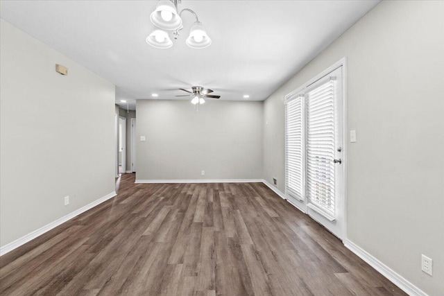 unfurnished living room with dark wood-type flooring and ceiling fan with notable chandelier