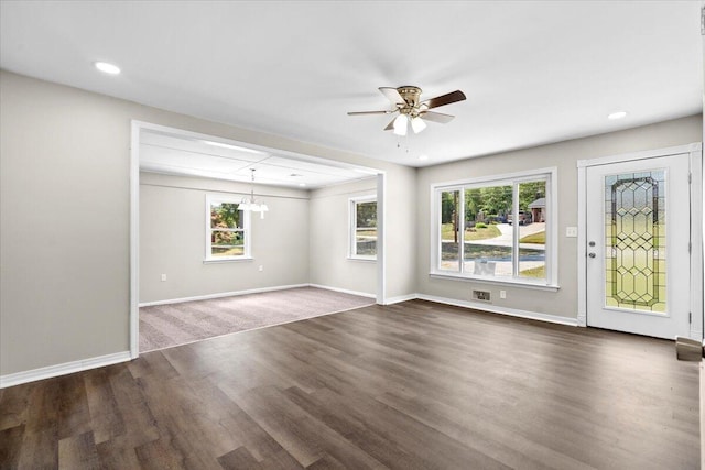 unfurnished living room featuring dark hardwood / wood-style flooring and ceiling fan with notable chandelier