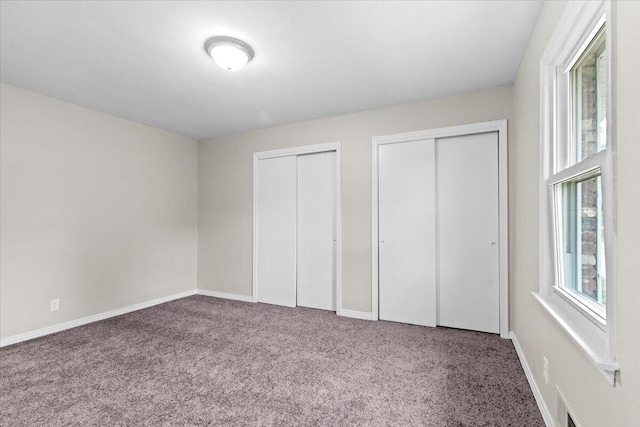 unfurnished bedroom with carpet floors and multiple closets