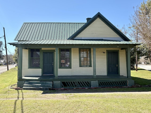 bungalow-style home with metal roof, covered porch, and a front lawn