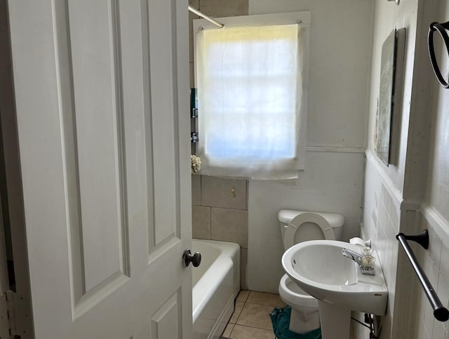 bathroom with tile patterned floors, toilet, a tub to relax in, and tile walls