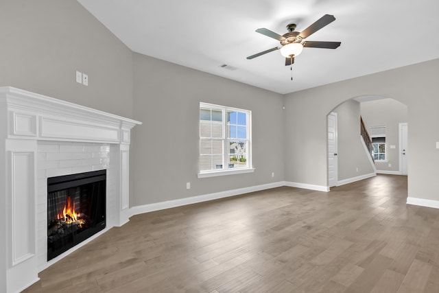 2767 Huntcliffe Dr, Augusta, GA 30909 - unfurnished living room featuring visible vents, arched walkways, ceiling fan, wood finished floors, and a lit fireplace