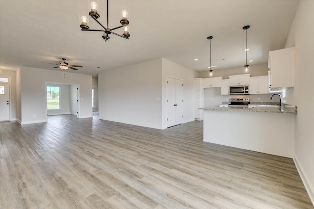 kitchen featuring white cabinetry, hanging light fixtures, light stone counters, ceiling fan with notable chandelier, and appliances with stainless steel finishes