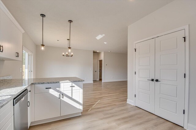 empty room featuring ceiling fan with notable chandelier and light wood-type flooring