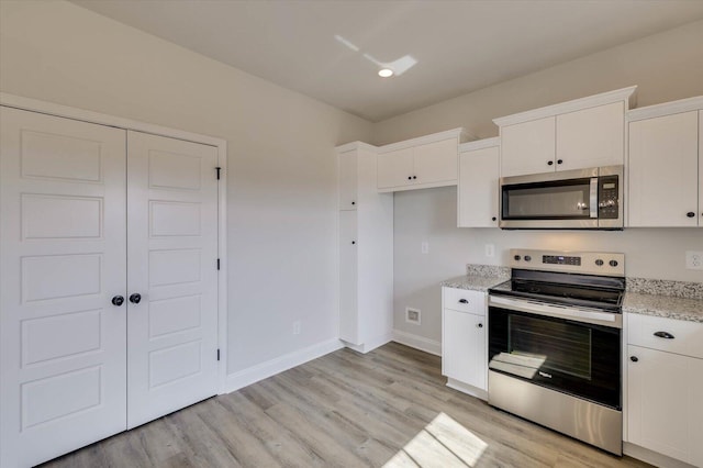 kitchen featuring stainless steel appliances, white cabinetry, and light hardwood / wood-style flooring